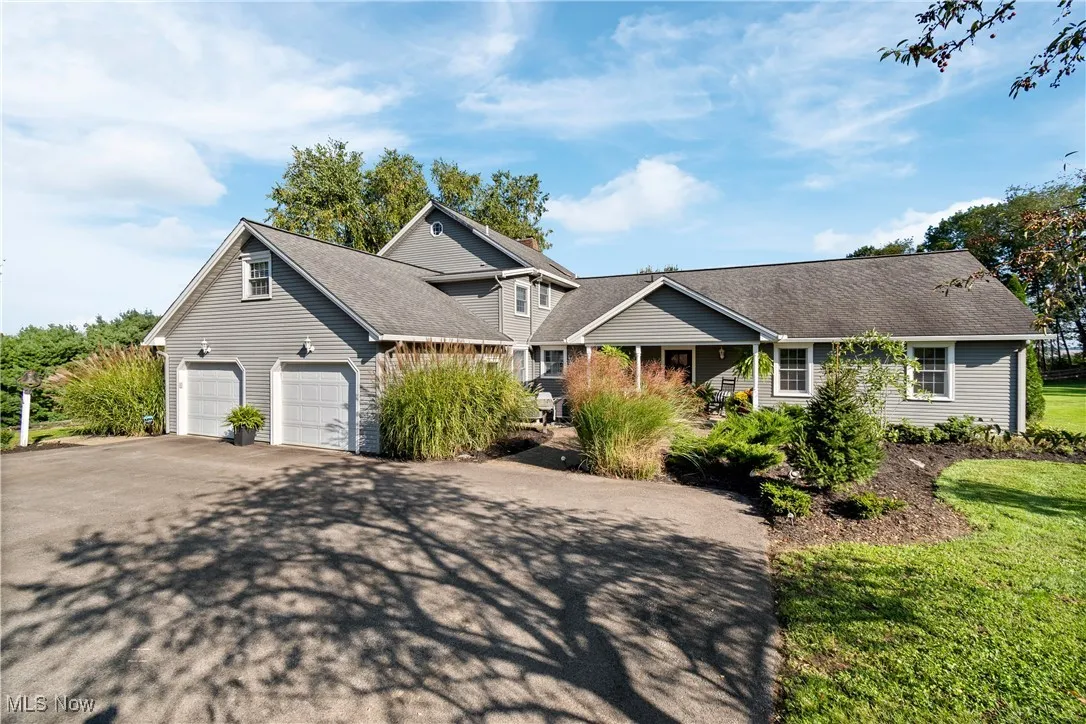 Traditional-style home with driveway, a garage, and roof with shingles
