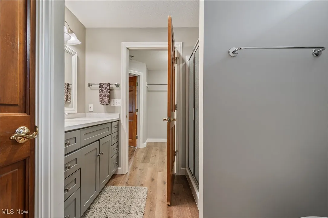 Bathroom featuring vanity, a stall shower, and wood finished floors