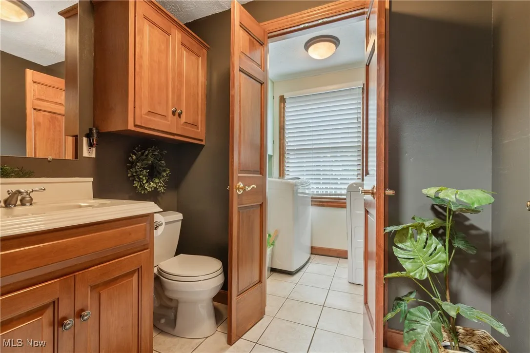 Bathroom featuring vanity, tile patterned floors, and washing machine and clothes dryer