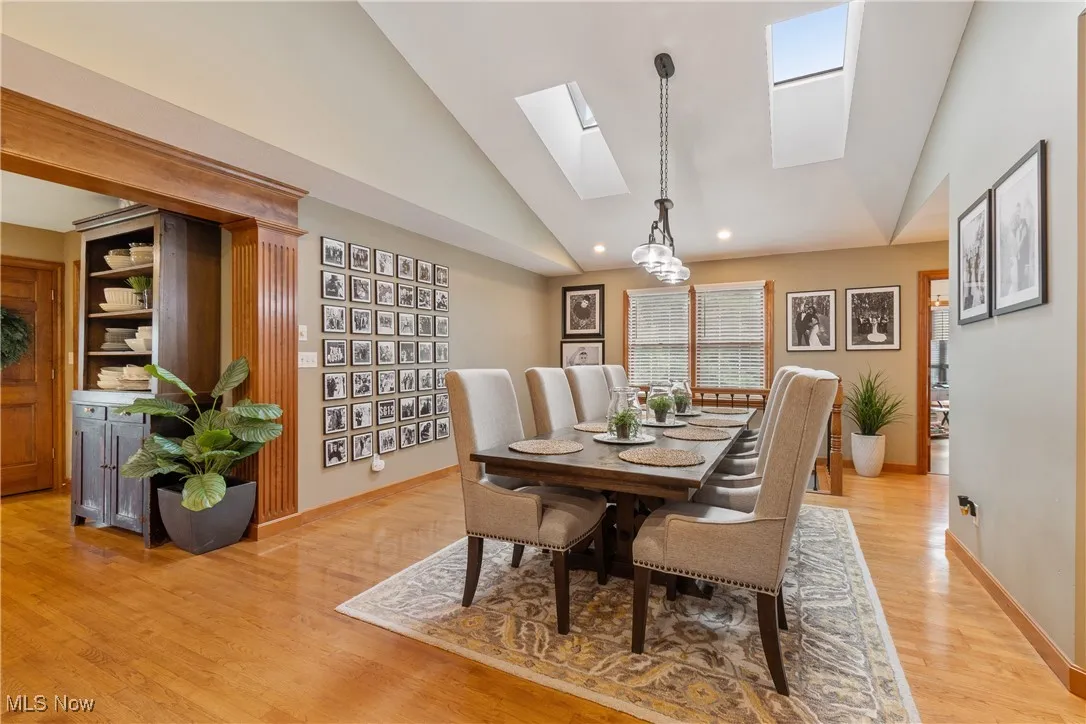 Dining space featuring a skylight, light wood-style floors, high vaulted ceiling, and recessed lighting