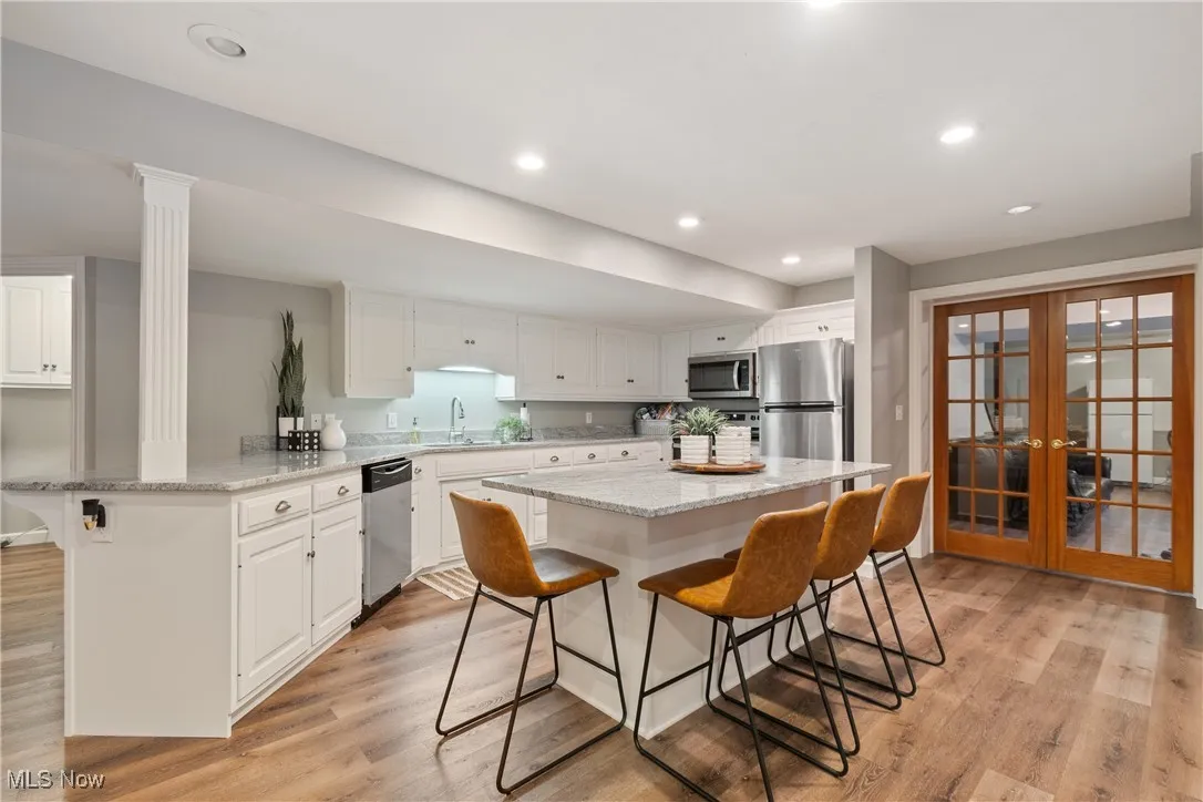 Kitchen with a breakfast bar area, french doors, white cabinetry, and recessed lighting