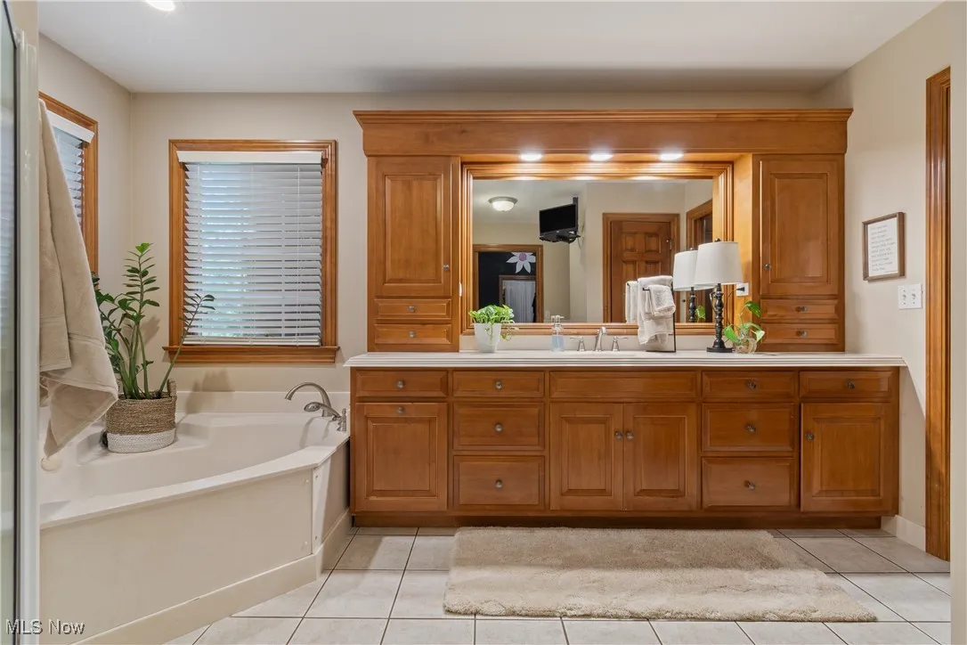 Full bathroom featuring vanity, tile patterned flooring, and a garden tub
