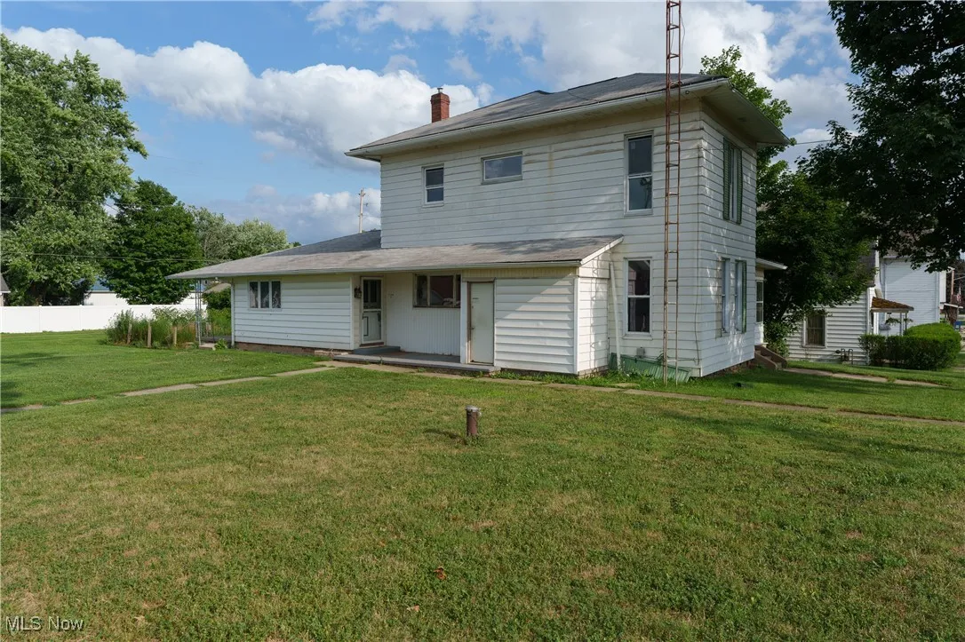 Rear view of property with a chimney and a yard