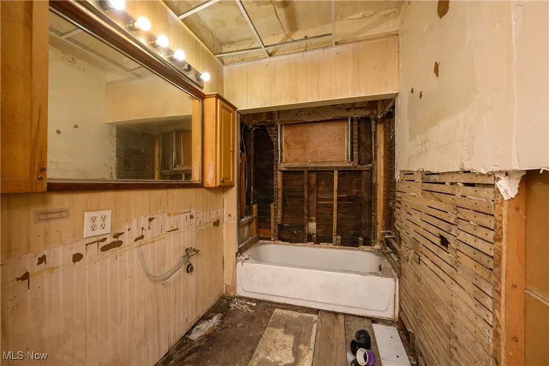 Full bathroom with a bathtub and wooden walls