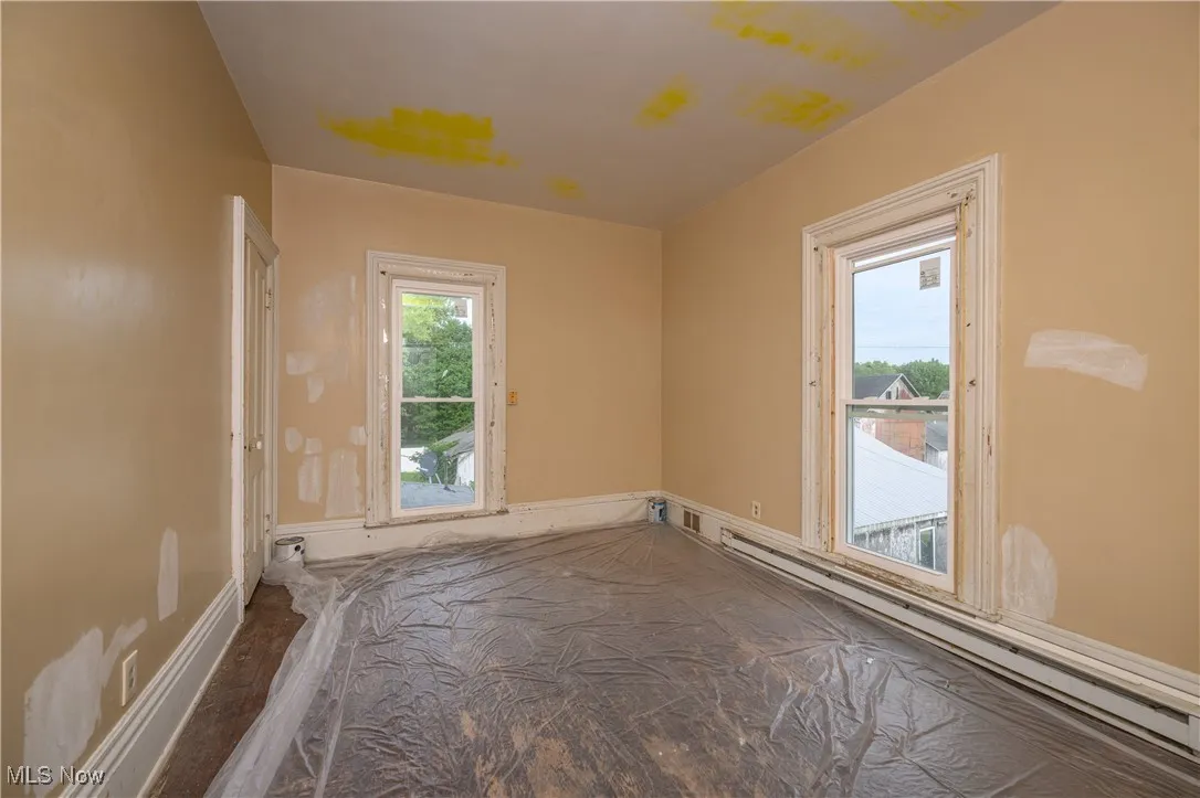 Empty room with baseboard heating and wood finished floors