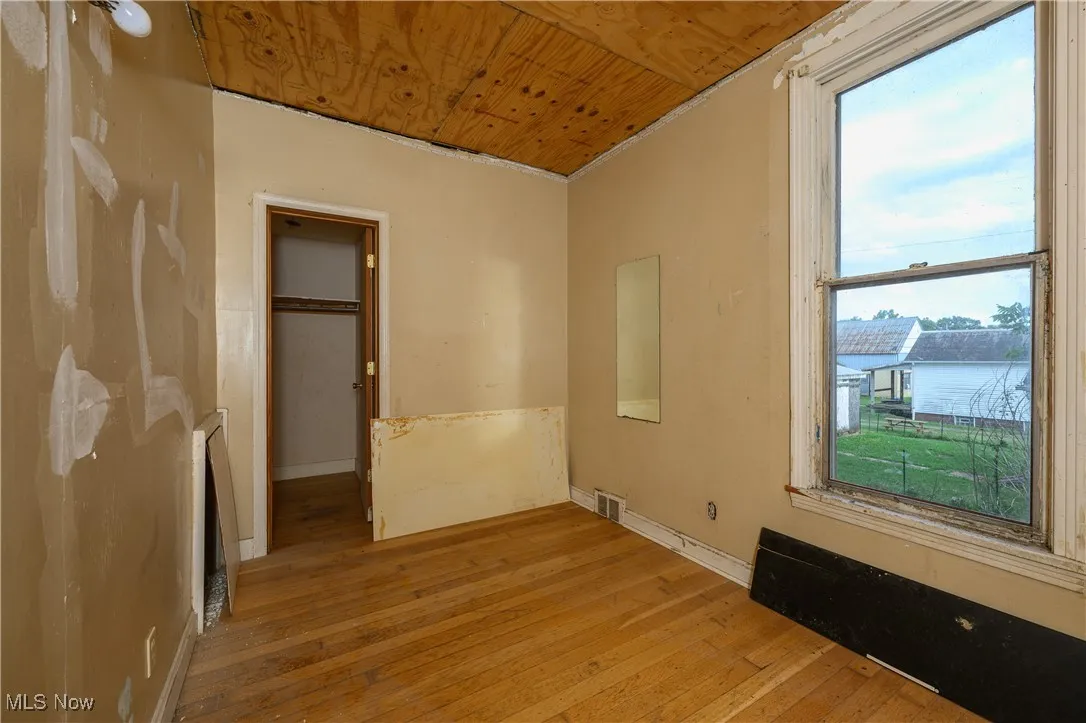 Unfurnished bedroom featuring wood ceiling, light wood-style floors, and a walk in closet