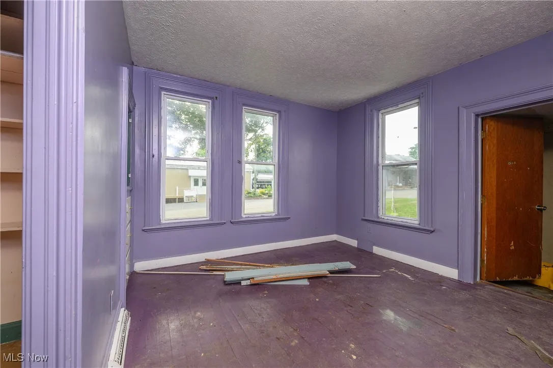 Empty room featuring hardwood / wood-style flooring, a textured ceiling, and plenty of natural light