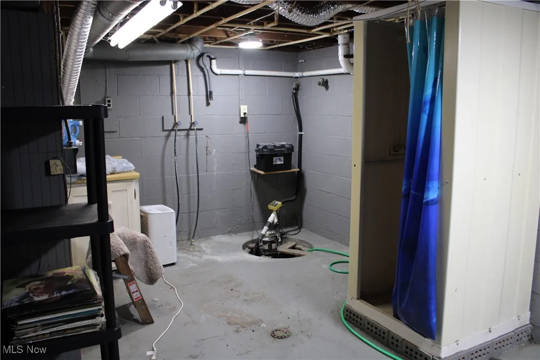 Unfinished below grade area featuring concrete block wall and drainage system