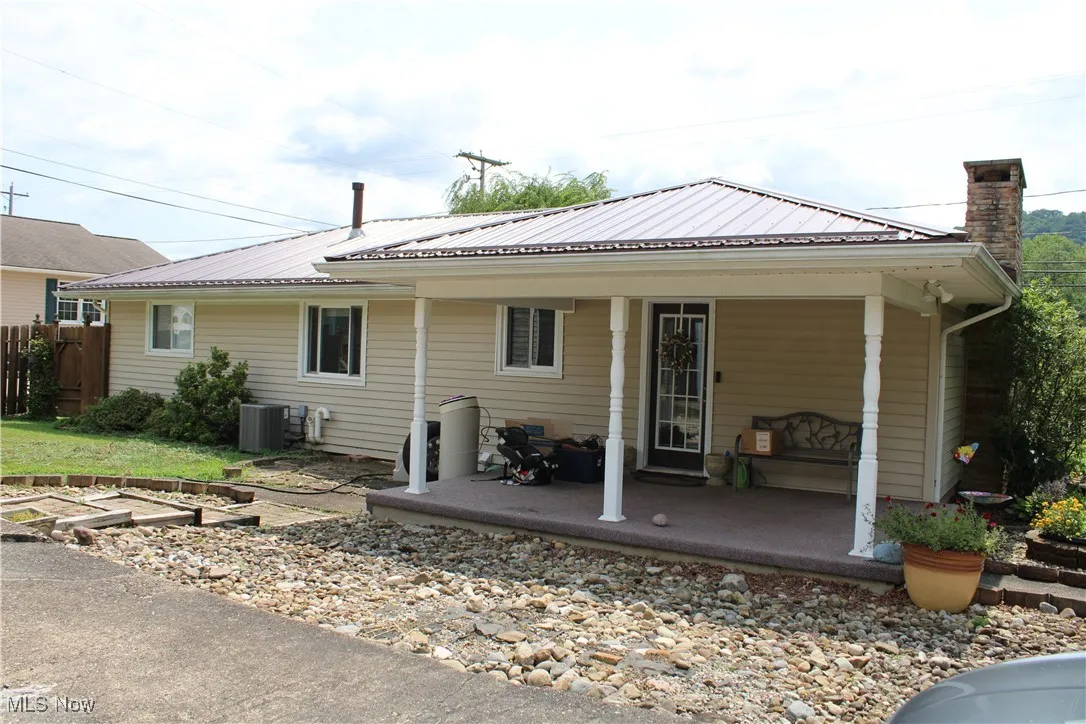 Back of house with covered porch, a chimney, a metal roof, and a vegetable garden