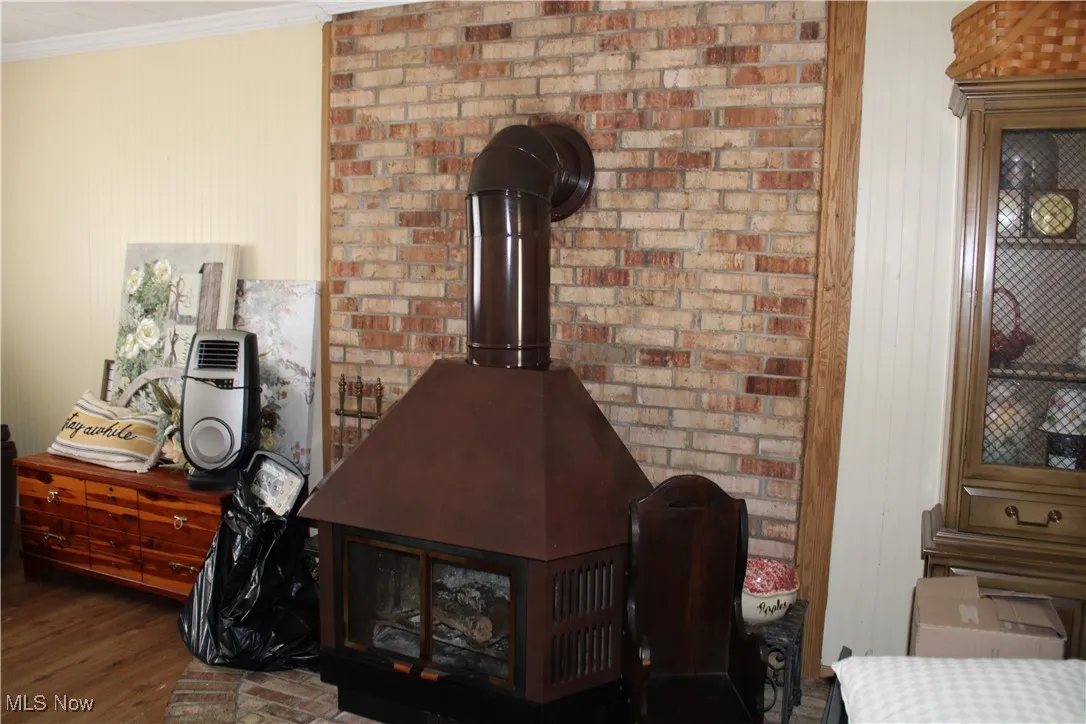Detailed view of wood finished floors, ornamental molding, wood walls, and a wood stove