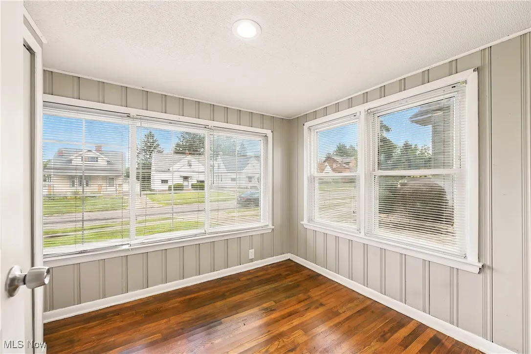 Unfurnished sunroom with hardwood / wood-style floors, a decorative wall, and a textured ceiling