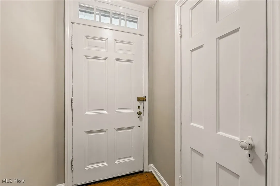 Doorway with baseboards and dark wood-style flooring