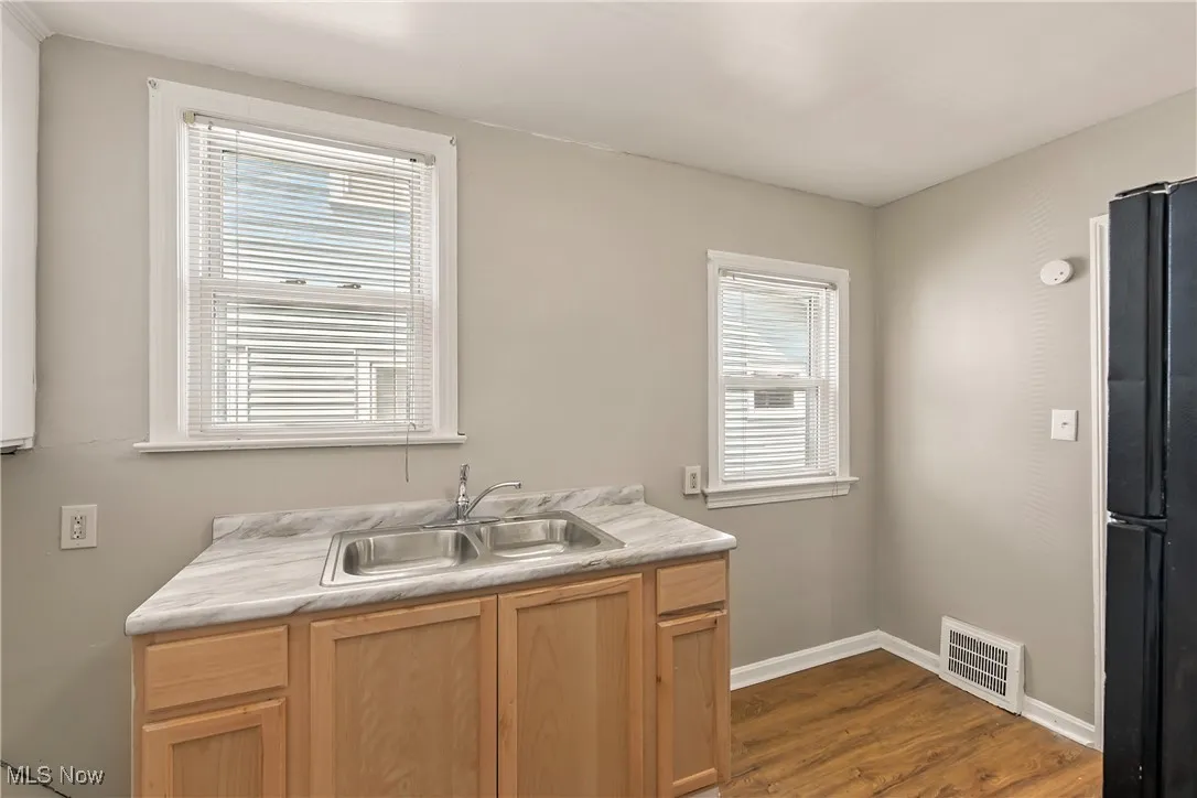 Kitchen with dark wood-style floors, freestanding refrigerator, light countertops, and light brown cabinets