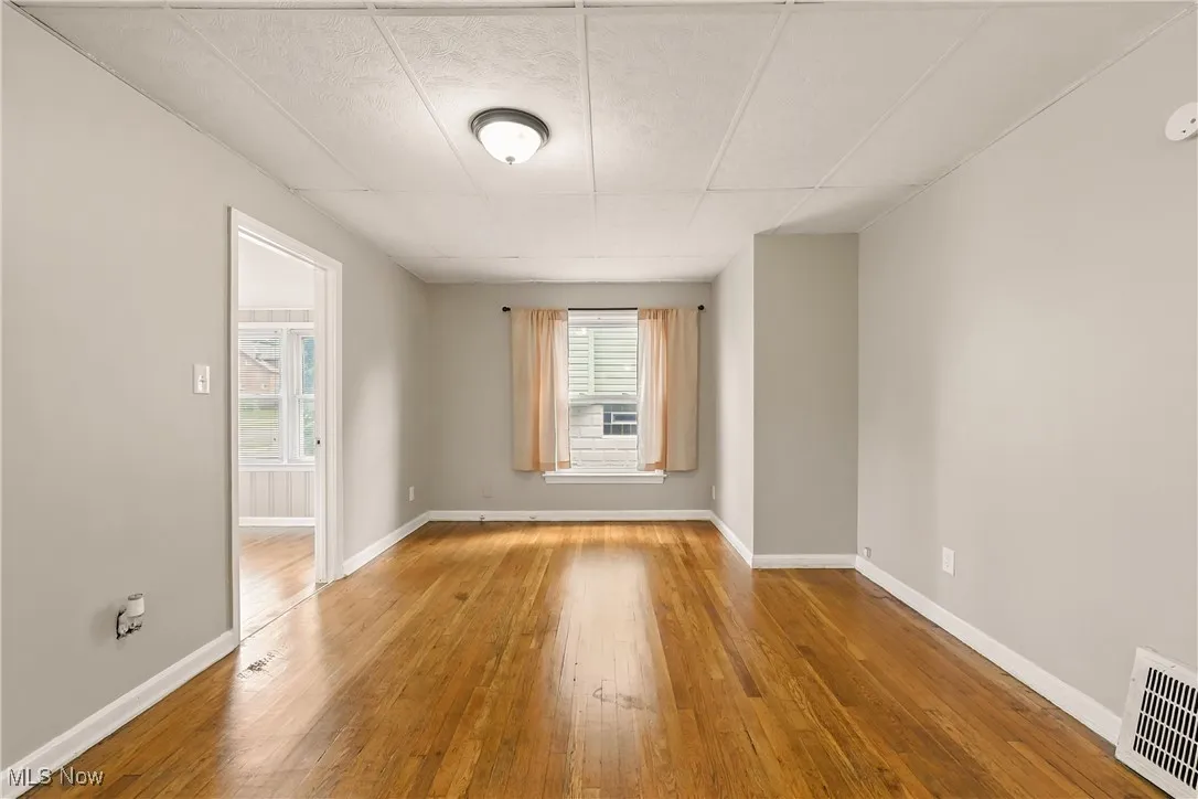 Spare room featuring wood-type flooring and baseboards