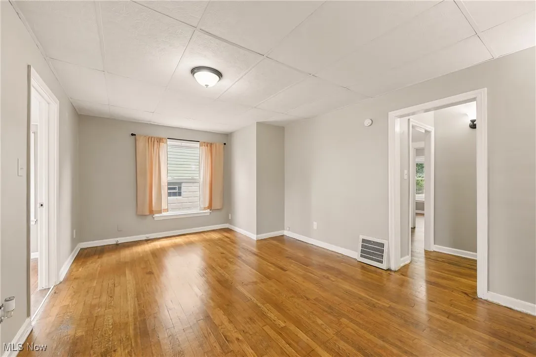 Unfurnished room with hardwood / wood-style floors and a paneled ceiling