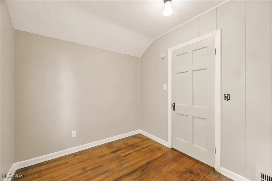 Spare room with dark wood-style floors and vaulted ceiling