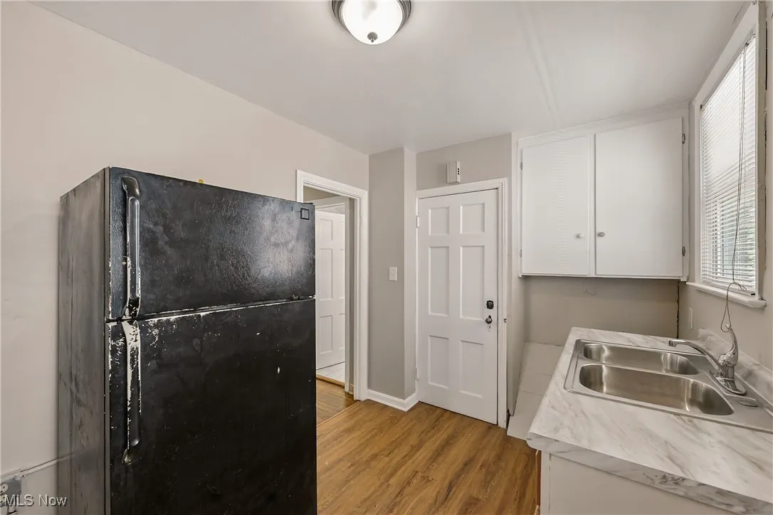 Kitchen featuring freestanding refrigerator, white cabinetry, light wood-style floors, and light countertops