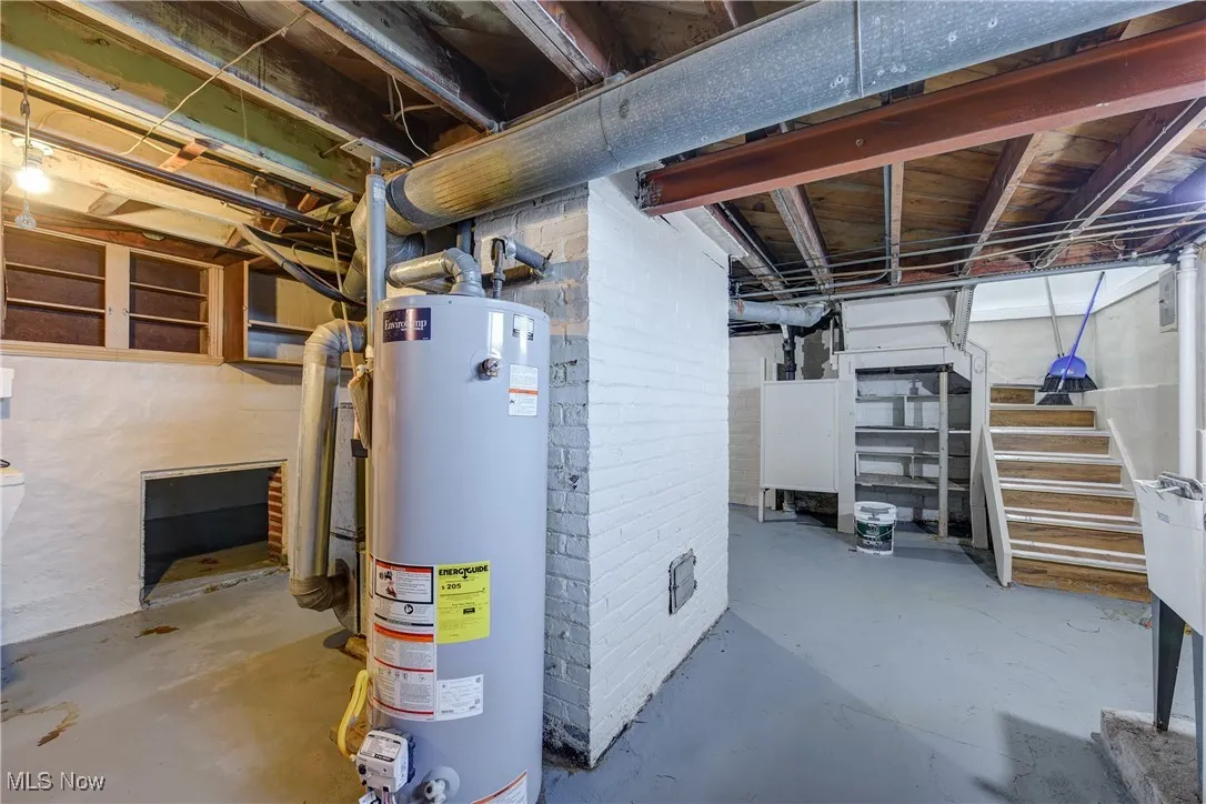 Unfinished below grade area featuring water heater and stairs
