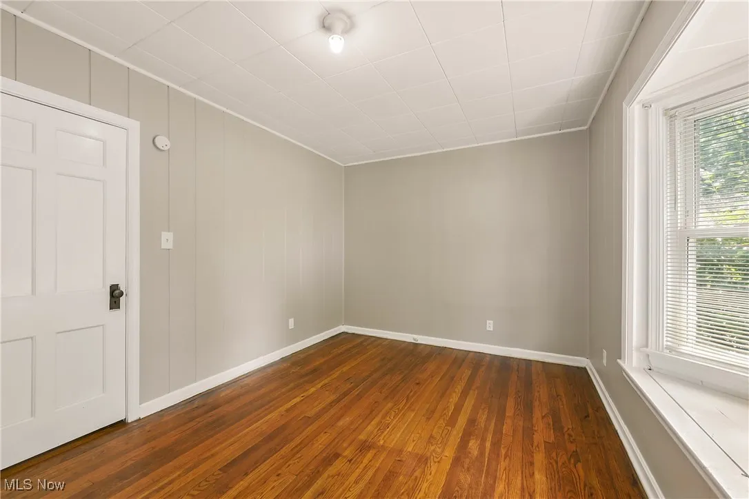 Empty room with dark wood-type flooring and baseboards