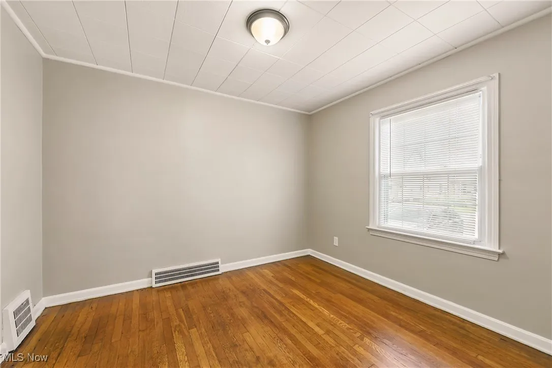 Empty room with ornamental molding and wood-type flooring