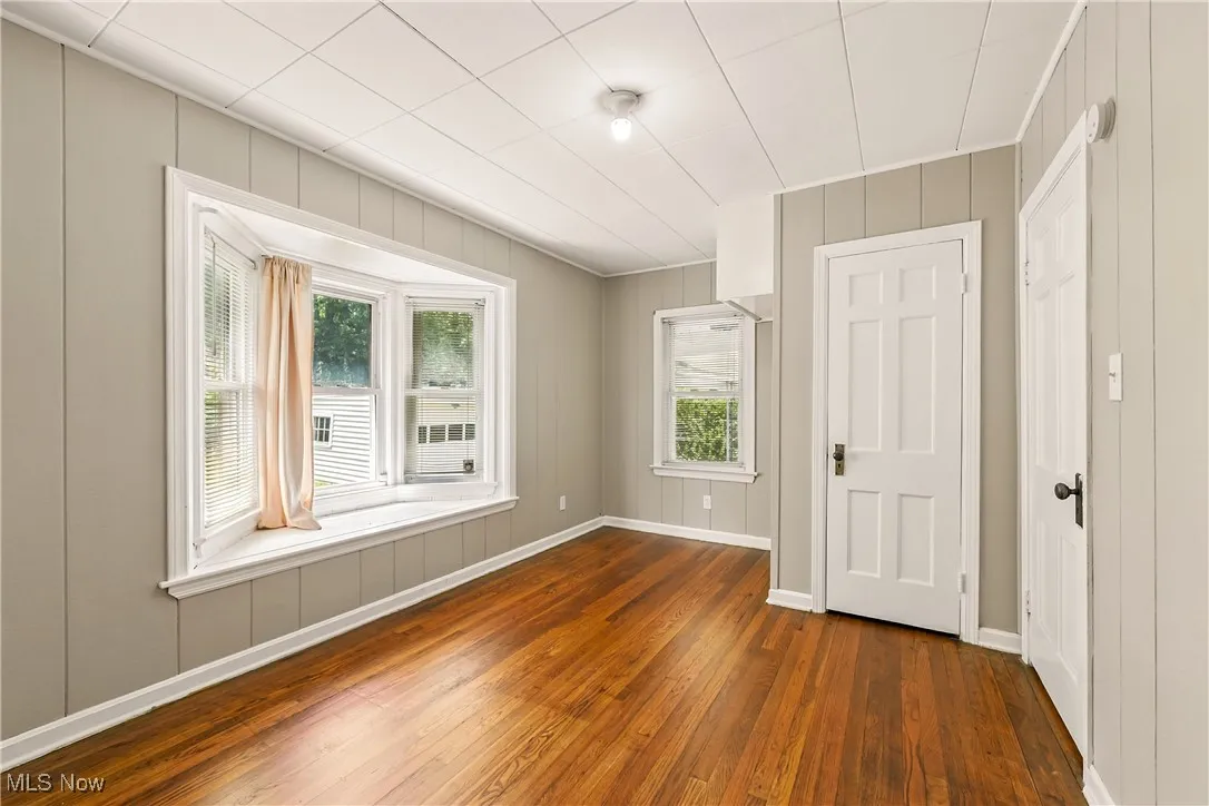 Empty room featuring dark wood-style flooring and a decorative wall