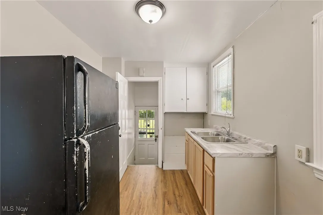 Kitchen with freestanding refrigerator, light wood finished floors, healthy amount of natural light, and light countertops