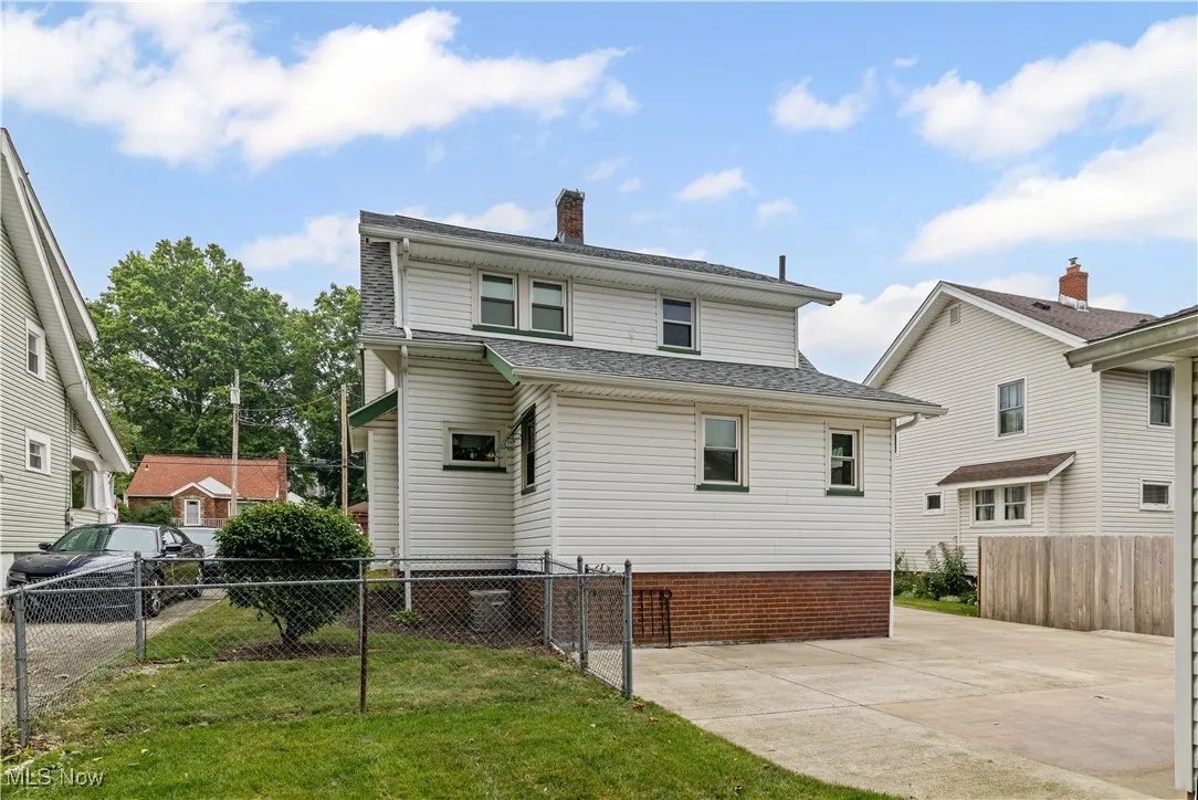 Back of house with a chimney, a patio, roof with shingles, and driveway