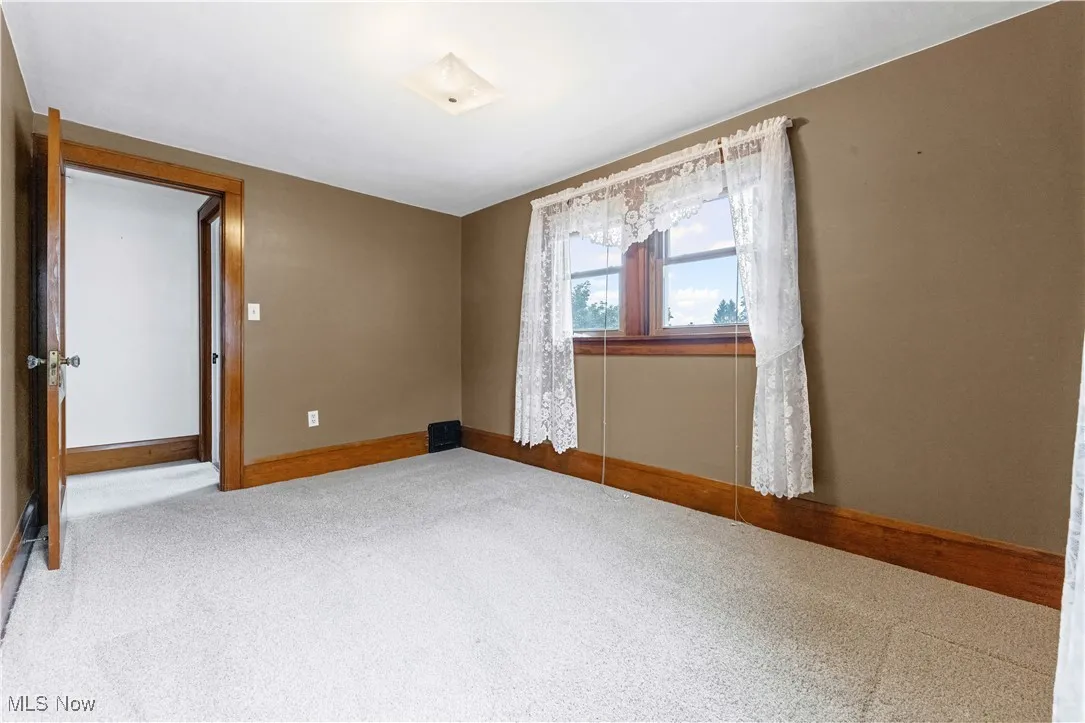 Carpeted empty room featuring baseboards