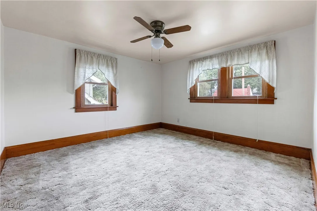Empty room with plenty of natural light, carpet flooring, and a ceiling fan