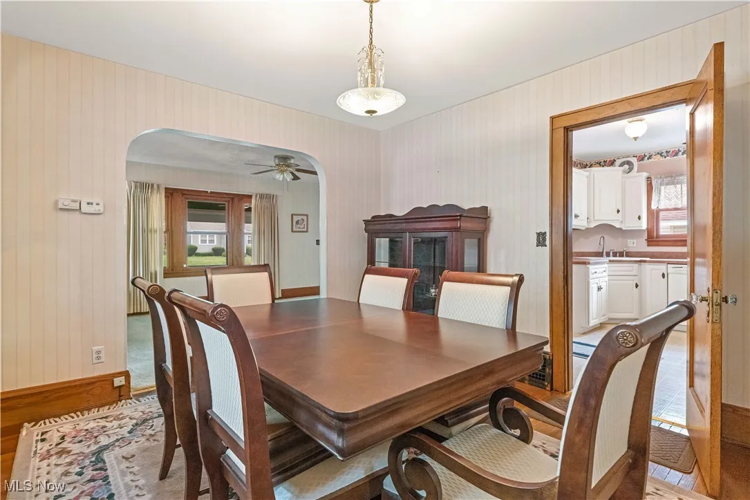 Dining space featuring arched walkways, wallpapered walls, and ceiling fan