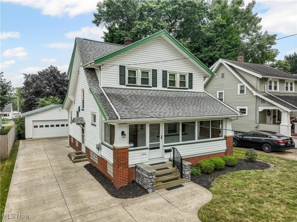 View of front of house featuring a shingled roof, an outdoor structure, a garage, and a front yard