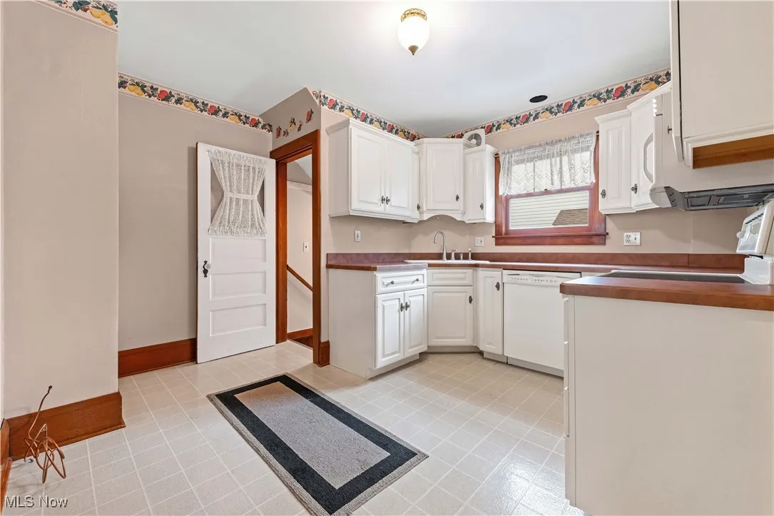 Kitchen with dishwasher, white cabinetry, stove, and dark countertops