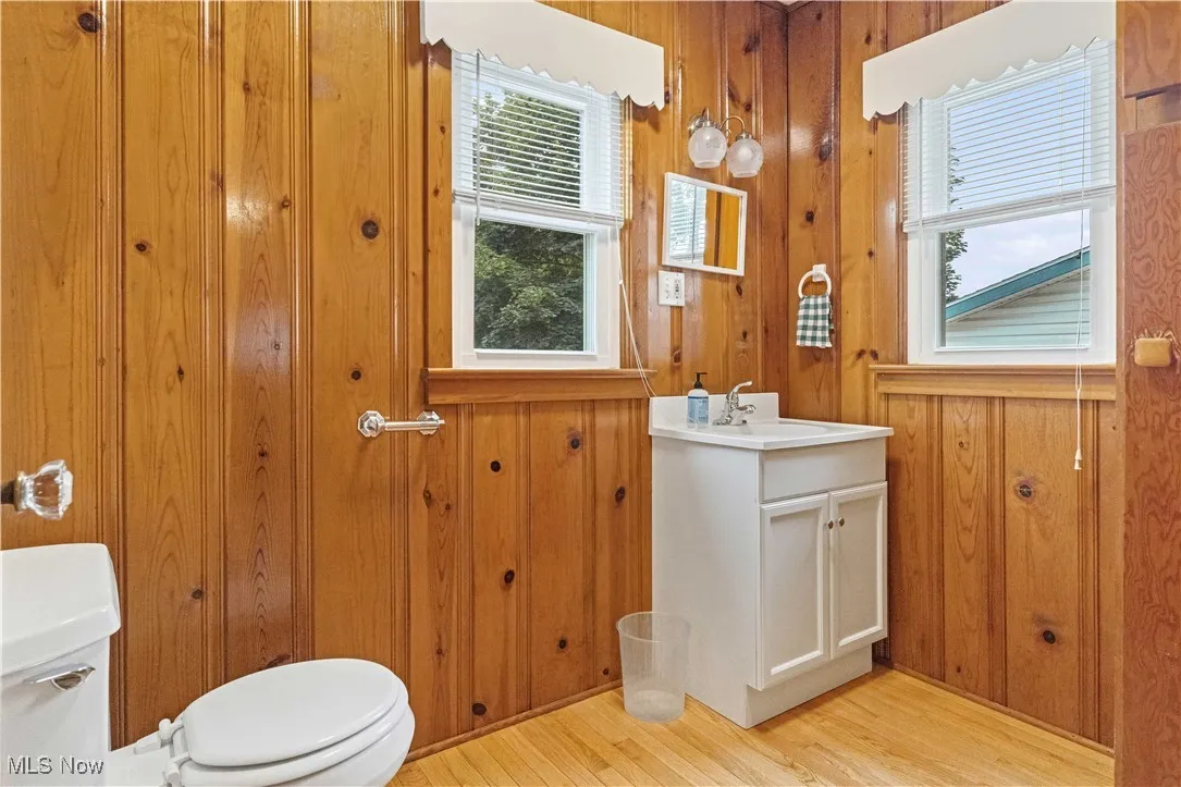 Half bathroom with wood finished floors, vanity, and wooden walls