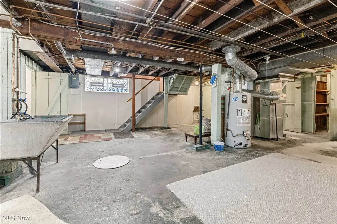 Basement featuring stairway, heating unit, and gas water heater