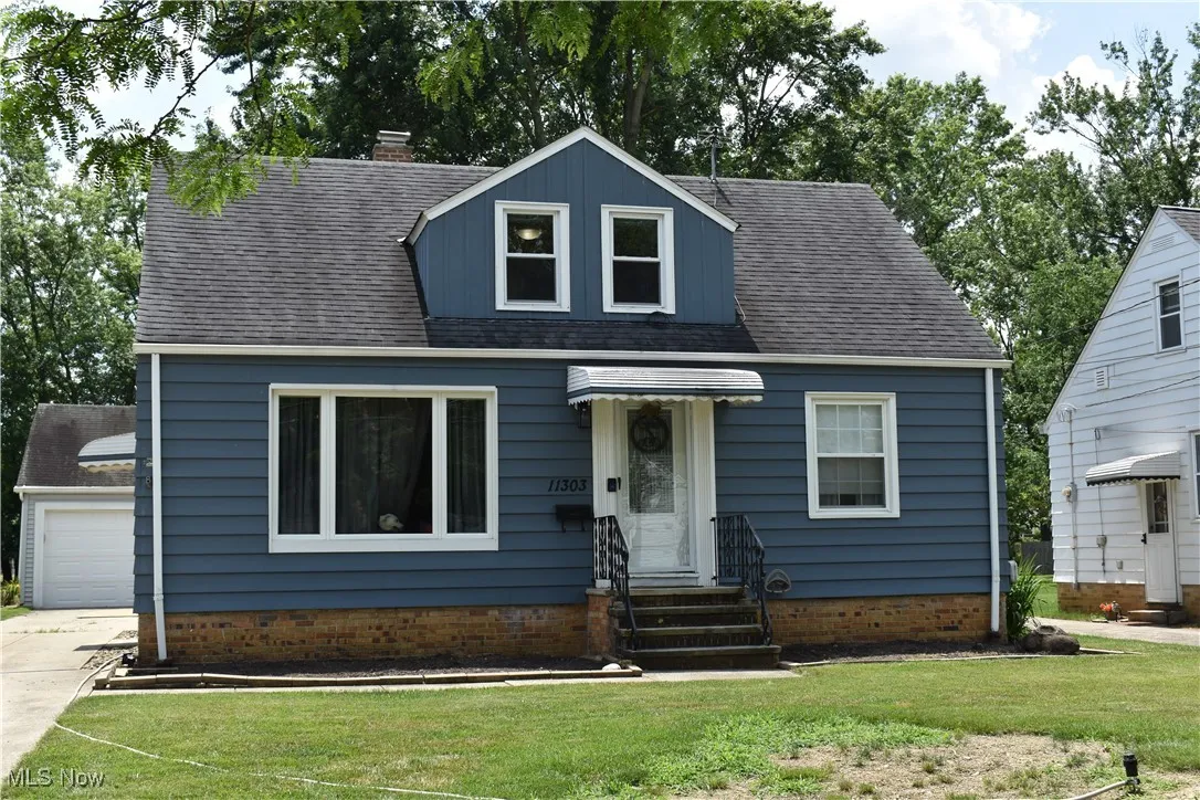 View of front of property featuring entry steps, a shingled roof, a front yard, and a chimney