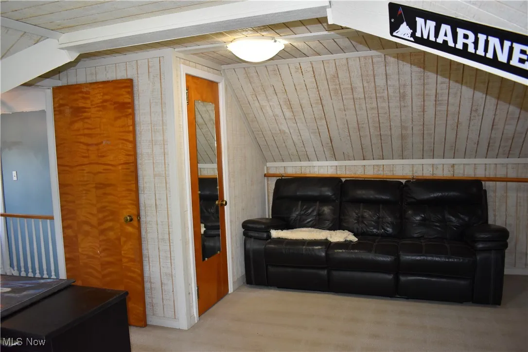 Bedroom featuring vaulted ceiling, wooden ceiling, wooden walls, and carpet flooring
