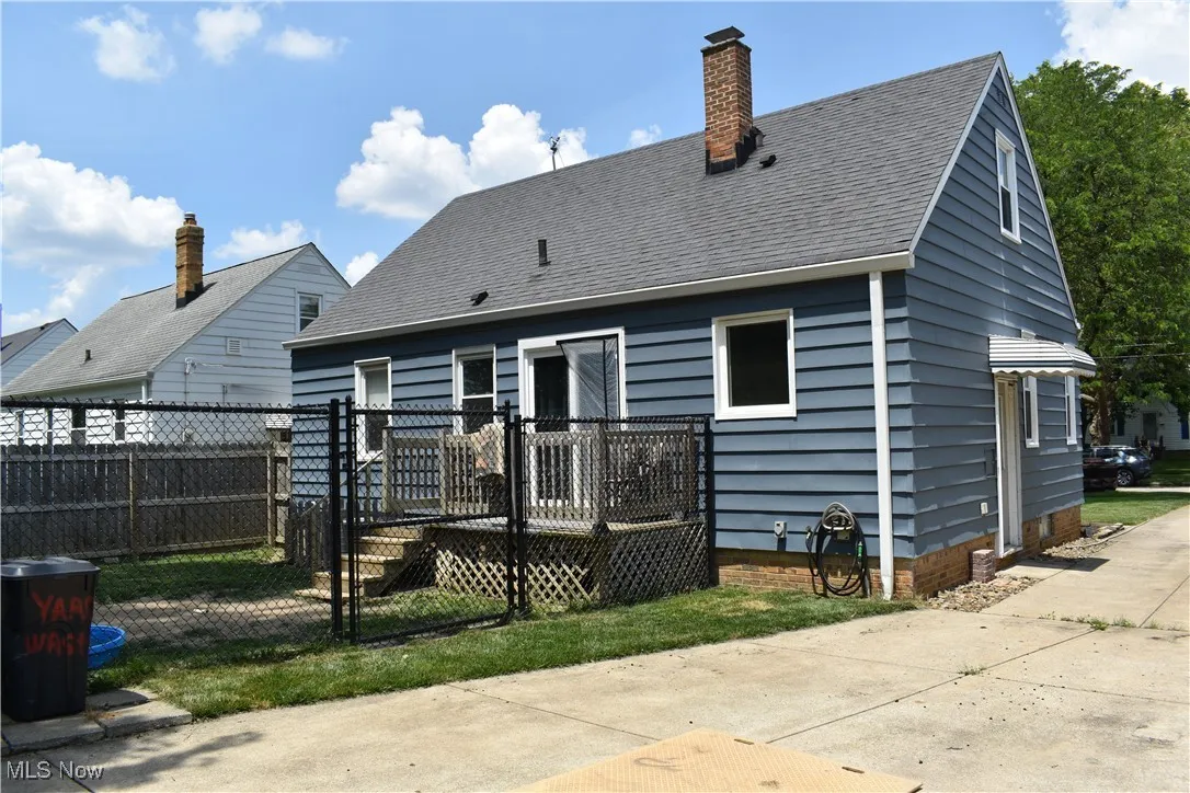 Rear view of house with a wooden deck, roof with shingles, and a chimney