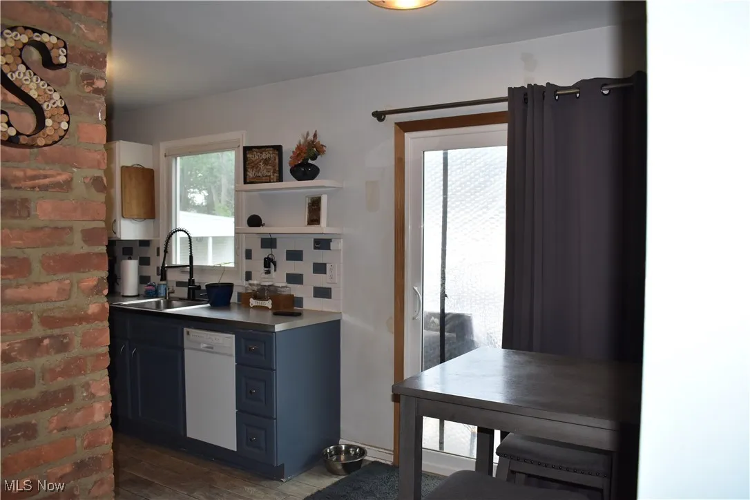 Kitchen featuring dishwasher, decorative backsplash, and dark wood-type flooring