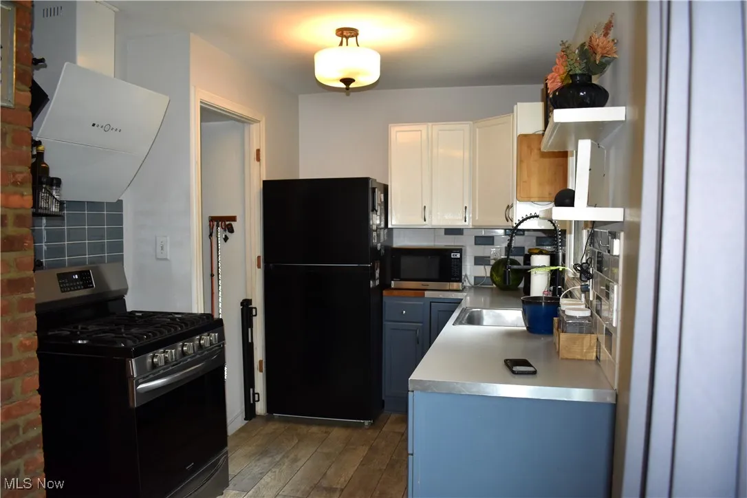 Kitchen featuring stainless steel appliances, extractor fan, tasteful backsplash, and white cabinets
