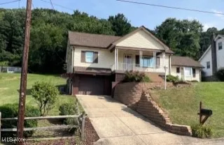 View of front of home with driveway, an attached garage, and covered porch