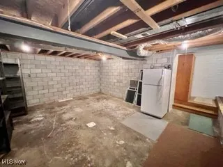 Unfinished basement featuring freestanding refrigerator