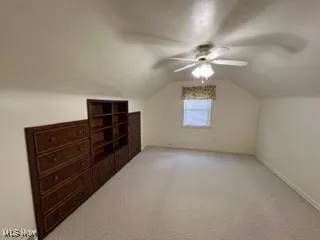 Bonus room featuring a ceiling fan, vaulted ceiling, and light colored carpet