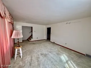 Unfurnished room featuring stairs and carpet floors