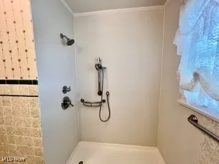 Bathroom featuring a tile shower and ornamental molding