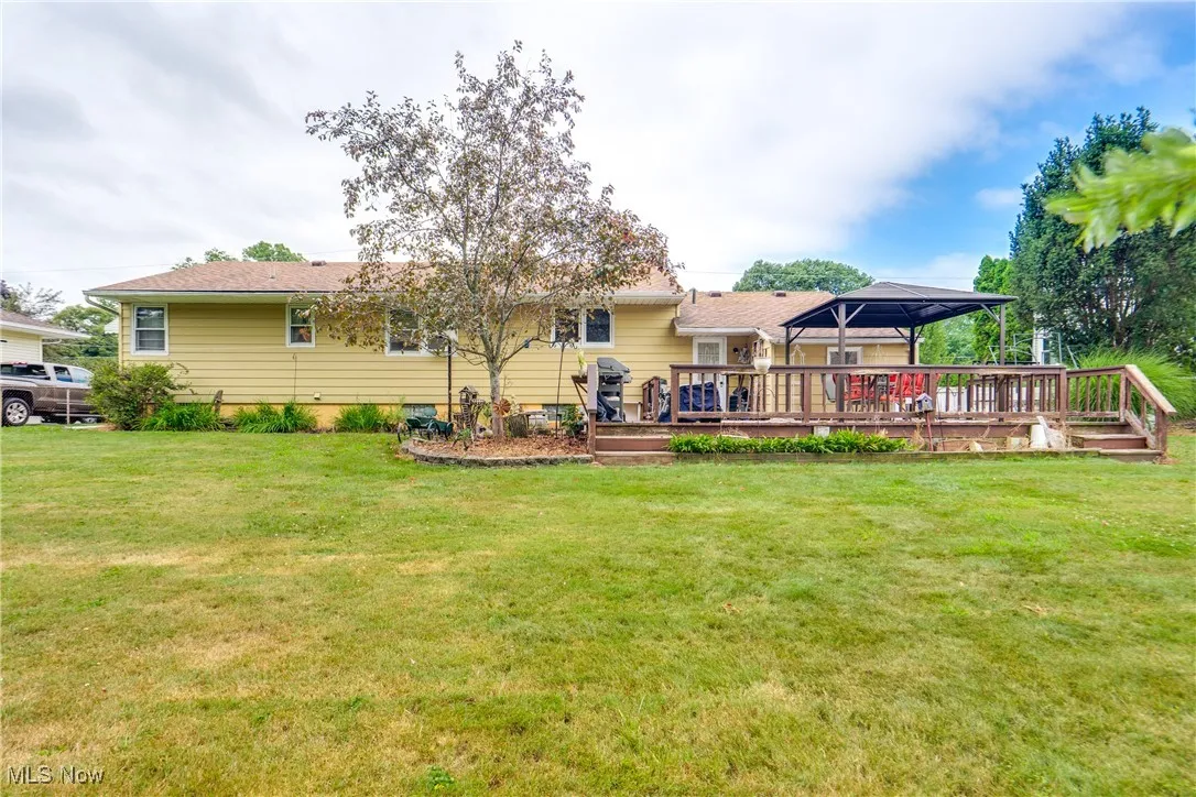 Rear view of house with a gazebo, a lawn, and a wooden deck