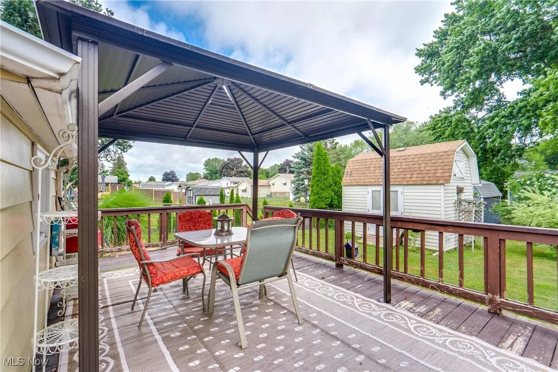 Deck with a gazebo, outdoor dining area, and a residential view