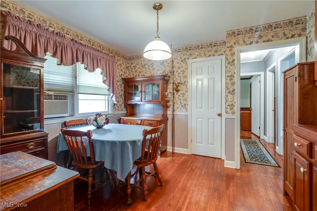 Dining area featuring wallpapered walls, a wainscoted wall, wood finished floors, and cooling unit