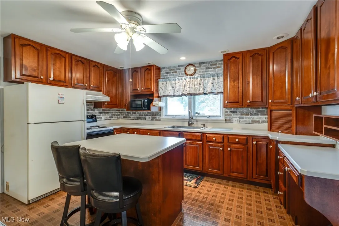 Kitchen featuring white appliances, light countertops, ceiling fan, and recessed lighting