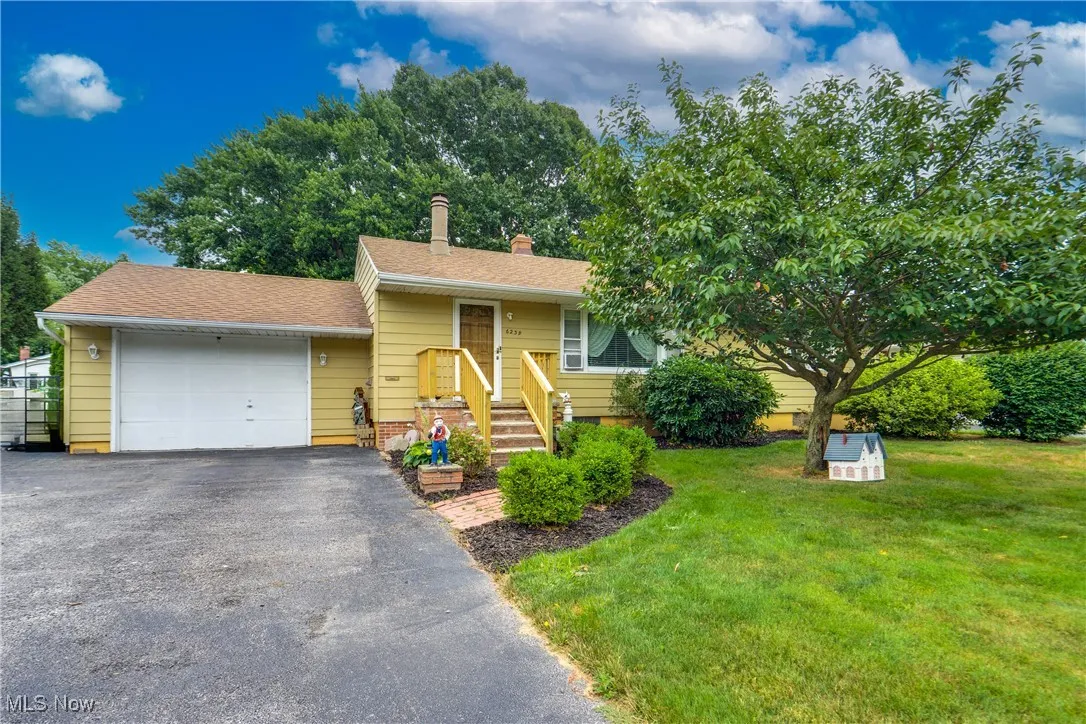 View of front of home featuring a front yard, asphalt driveway, an attached garage, and roof with shingles