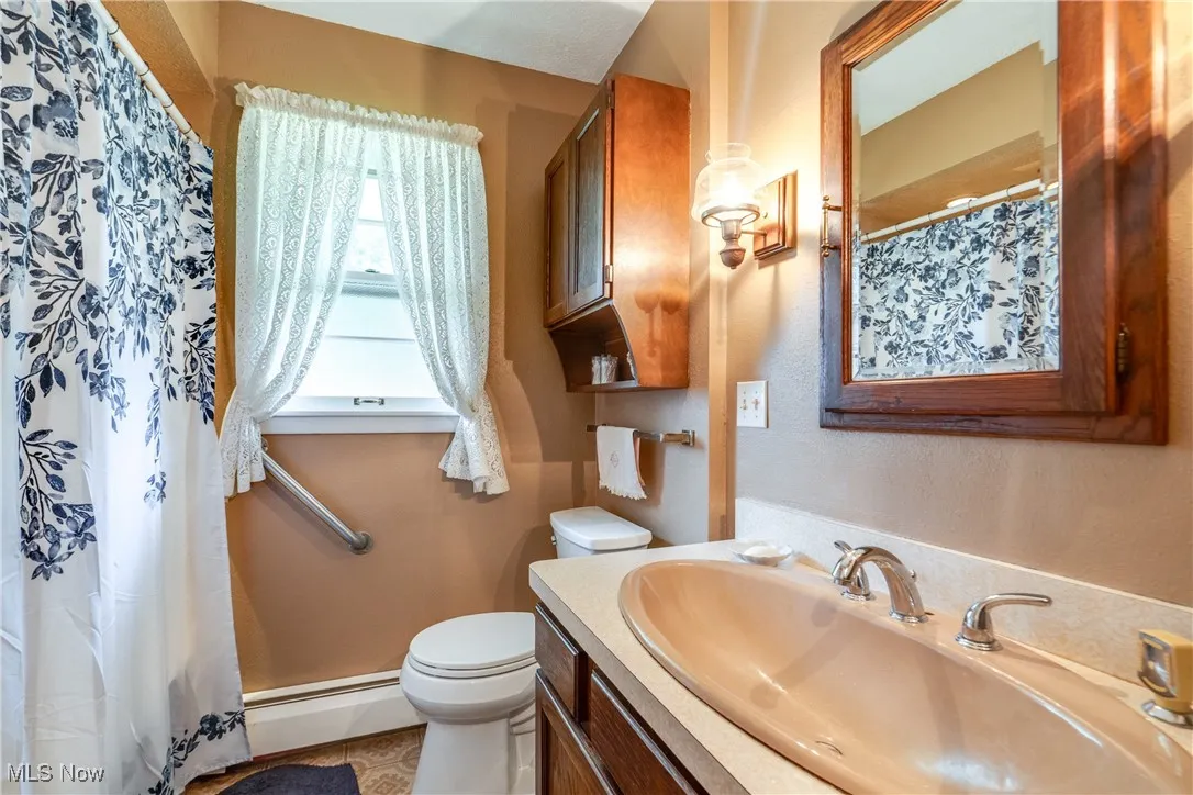 Full bathroom featuring vanity, curtained shower, and a baseboard radiator